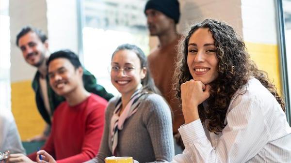 Diverse group of young adults in well lit room, smiling